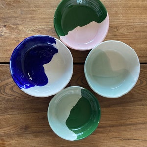 Può includere: Quattro ciotole in ceramica con base bianca e un solo colore di vernice sulla metà superiore di ogni ciotola. I colori sono verde, blu, verde chiaro e rosa.