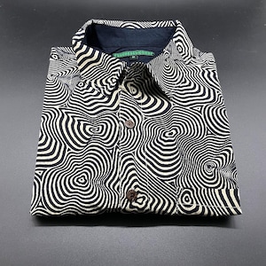 Peut inclure: Une chemise boutonnée noire et blanche avec un motif psychédélique tourbillonnant. La chemise a une étiquette verte qui indique "PSYCHEDELIC SHOP" et une étiquette de taille "M".