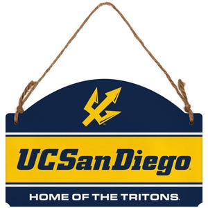 May include: A rectangular hanging sign with a rounded top, featuring a dark blue background with a yellow trident logo. The center displays the text UC San Diego in dark blue on a yellow band, with HOME OF THE TRITONS in white below.