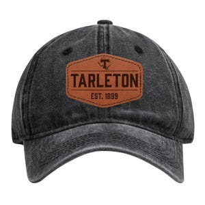 May include: A black, distressed baseball cap with a curved brim. The cap features a brown leather patch with the word "TARLETON" in bold letters, the university's logo, and "EST. 1899".