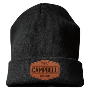 May include: A black knit beanie featuring a brown faux leather patch in a hexagonal shape. The patch displays a graphic of a running dog above the text CAMPBELL and EST. 1887 in dark brown lettering. The beanie has a folded cuff design.