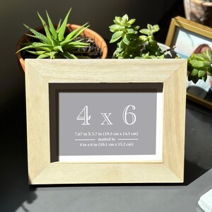 a picture frame sitting on top of a table next to a potted plant