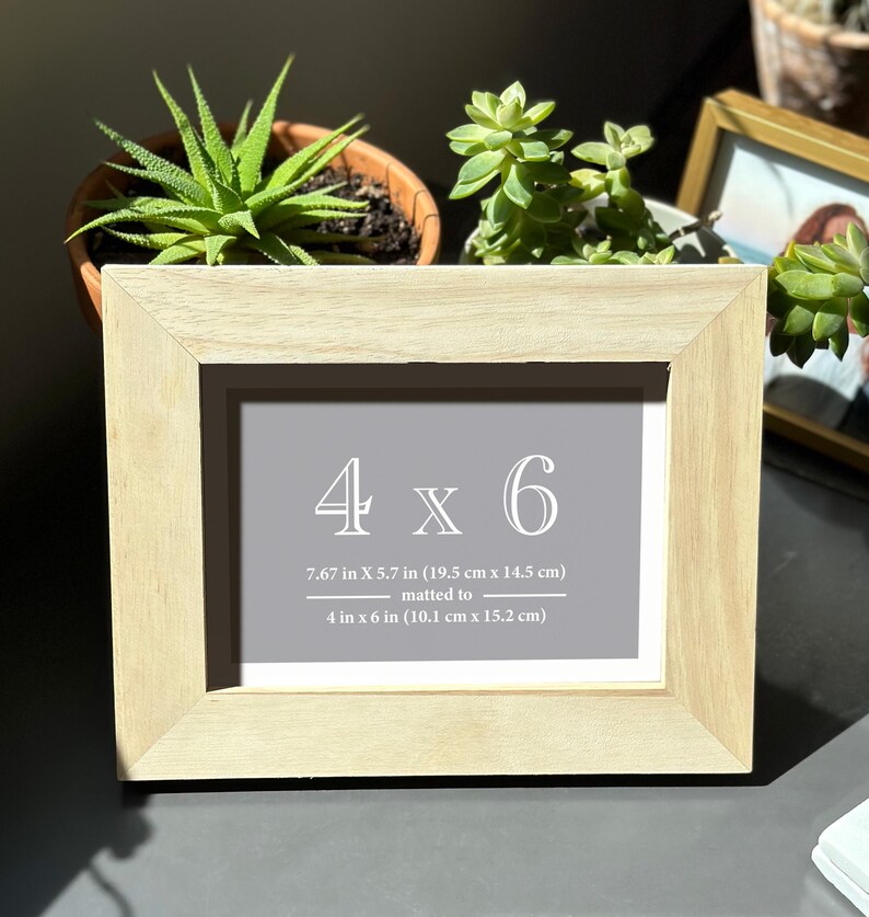 a picture frame sitting on top of a table next to a potted plant
