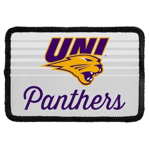 May include: A rectangular patch with a black stitched border featuring a white background with horizontal light gray stripes. The design includes the purple text UNI above a yellow panther head graphic and the purple script text Panthers below.
