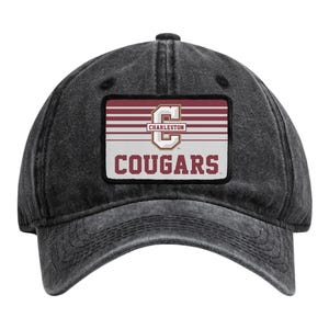 May include: A charcoal grey baseball cap with a distressed finish. Centered on the front is a rectangular patch featuring a maroon and white striped background, a large letter C, the word CHARLESTON, and the word COUGARS in maroon lettering.