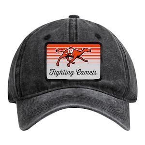 May include: A charcoal grey washed baseball cap featuring a rectangular patch on the front. The patch displays an orange camel graphic over horizontal orange and white stripes, with the text Fighting Camels written in black script below.