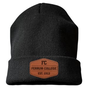 May include: A black knit beanie featuring a brown faux leather patch on the front cuff. The patch is hexagonal and displays the text FC, FERRUM COLLEGE, and EST. 1913 in dark brown lettering. The beanie has a ribbed texture and a folded brim.