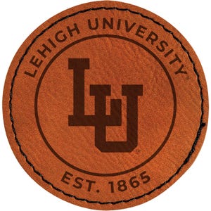 May include: A round, brown leather patch featuring the Lehigh University logo. The logo includes the letters "LU" in a dark brown font, surrounded by the words "LEHIGH UNIVERSITY" and "EST. 1865" in a circular design, with black stitching around the edge.