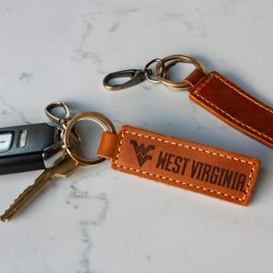 two leather keychains with two keys attached to them
