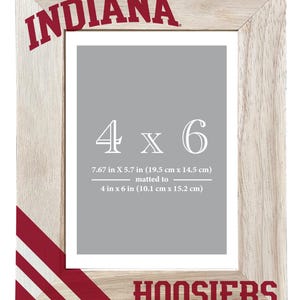 May include: Wooden photo frame with the word "INDIANA" in red at the top and "HOOSIERS" at the bottom. The frame is designed for a 4 x 6 inch photo, with the dimensions of the frame being 7.67 x 5.7 inches.