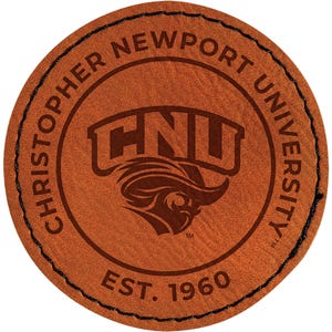 May include: A round, brown leather patch with black stitching around the edge. The patch features the words "CHRISTOPHER NEWPORT UNIVERSITY" around the perimeter, with "CNU" and a logo in the center, and "EST. 1960" at the bottom.