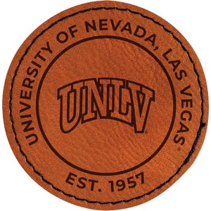 May include: A round, brown leather patch with the text "UNIVERSITY OF NEVADA, LAS VEGAS" around the edge. The letters "UNLV" are in the center, with "EST. 1957" below. The patch has a stitched black border.