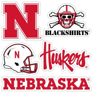 May include: A collection of red and white stickers featuring the University of Nebraska Cornhuskers. Designs include the letter "N", a football helmet, the word "Huskers", a skull wearing a helmet with crossed bones, the words "Blackshirts", and the word "Nebraska".