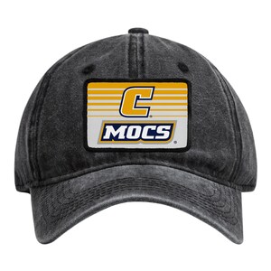 May include: A charcoal grey baseball cap with a distressed finish. Centered on the front is a rectangular patch featuring a yellow letter C above the word MOCS in blue and white lettering, set against a background of horizontal yellow stripes.