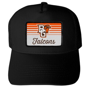 May include: A black trucker hat featuring a rectangular patch on the front. The patch displays the letters BG, a falcon head graphic, and the word Falcons in script text, set against a background of horizontal orange and white stripes.