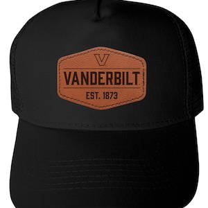 May include: Black baseball cap with a mesh back and a curved brim. The front features a brown leather patch with the word "VANDERBILT" and "EST. 1873" printed in dark brown. The cap has a snap closure.