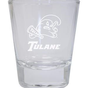 May include: A clear glass shot glass with a white Tulane University logo featuring a wave and a megaphone. The text "Tulane" is printed below the logo.