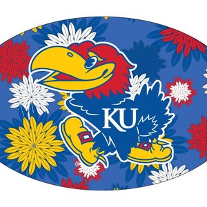 May include: A blue oval-shaped sticker with a cartoon blue and red bird mascot with the text "KU" on its chest. The background is a blue floral pattern with red, white, and yellow flowers.