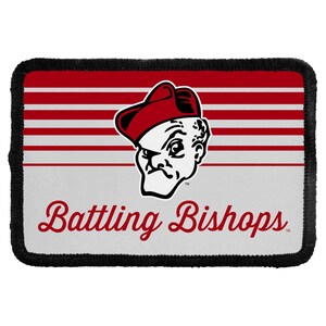 May include: A rectangular fabric patch with a black stitched border. The design features horizontal red and white stripes on the top half and a white bottom half. A graphic of a person in a red cap is centered, with the text Battling Bishops below.