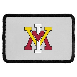May include: A rectangular patch with a light gray background and a thick black stitched border. Centered on the patch is a stylized logo featuring a large maroon letter M, a yellow letter V overlapping it, and a white letter I positioned vertically.