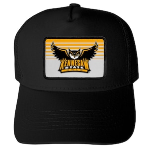 May include: A black baseball cap featuring a rectangular patch on the front. The patch displays a graphic of an owl with wings spread above the text KENNESAW STATE OWLS, set against a background of horizontal yellow and white stripes.