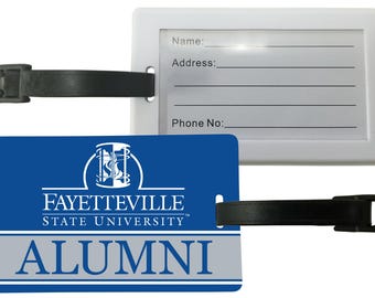 Pode incluir: Uma etiqueta de bagagem branca com uma alça e fivela pretas. Uma etiqueta azul com o logotipo da Universidade Estadual de Fayetteville e a palavra "ALUMNI" está anexada. A etiqueta tem espaço para nome, endereço e número de telefone.