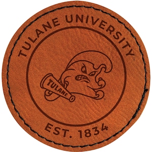 May include: A round, brown leather patch with the words "TULANE UNIVERSITY" around the outer edge. The Tulane mascot is in the center, holding a megaphone that says "TULANE". The text "EST. 1834" is at the bottom.