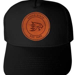 May include: Black baseball cap with a mesh back and a curved brim. The front features a circular brown leather patch with the words "CHICO STATE" and "EST. 1887" surrounding a cougar logo.