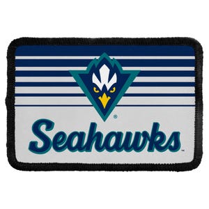 May include: A rectangular patch with a black stitched border. The top half features horizontal navy blue and white stripes. The center displays a stylized teal, navy, and yellow bird logo. The bottom half is white with the word Seahawks in blue.