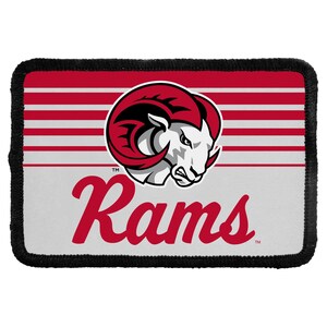 May include: A rectangular patch with a black stitched border featuring a red and white horizontal striped background. The center displays a white ram head logo with red horns and the red cursive text Rams positioned below the graphic.