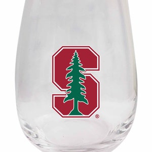 May include: A clear glass stemless wine glass with a red and green Stanford University logo. The logo features a stylized "S" with a green pine tree inside.