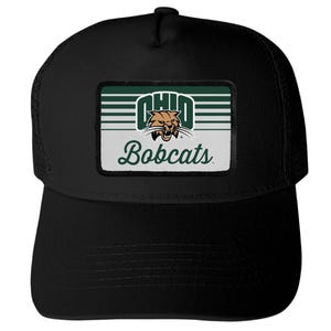 May include: A black baseball cap featuring a rectangular patch on the front. The patch displays the text OHIO in white block letters above a brown bobcat mascot graphic, with the word Bobcats in green script text below on a white background.