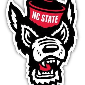 May include: A black and white wolf mascot with a red and black hat that says "NC STATE" on it. The wolf has a fierce expression with sharp teeth and a red tongue.