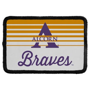 May include: A rectangular patch with a black stitched border. The top half features horizontal gold and white stripes. The center displays a large purple letter A with the word ALCORN in white text. The bottom half is white with the word Braves in purple.