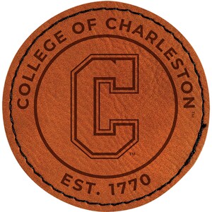 May include: A round, brown leather patch with the words "COLLEGE OF CHARLESTON" in a circular pattern around the edge. The center features a large, stylized letter "C" and the text "EST. 1770". The patch is stitched with black thread.