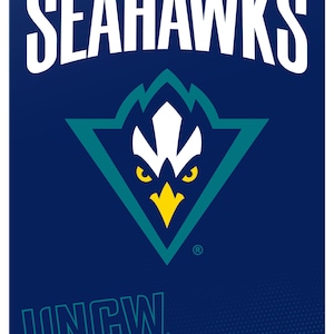 May include: A rectangular metal sign with the text "UNC WILMINGTON" and "SEAHAWKS" in white. The sign features a teal and white logo of a bird's head within a teal triangle on a navy blue background. The text "UNCW Seahawks" is at the bottom.