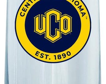 Puede incluir: Una flauta de champán de vidrio transparente con un logotipo amarillo y azul que dice "Central Oklahoma UCO Est. 1890"