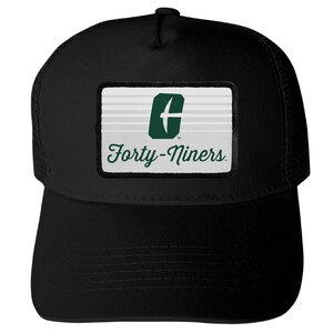 May include: A black baseball cap featuring a rectangular patch on the front. The patch has a white background with horizontal lines, a dark green letter C logo with a white bird silhouette, and the text Forty-Niners in dark green script.
