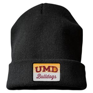May include: A black knit beanie featuring a rectangular patch on the front cuff. The patch displays the text UMD in bold maroon letters with a yellow outline, a small bulldog mascot graphic, and the word Bulldogs in maroon script below the text.