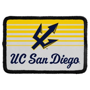 May include: A rectangular patch with a black stitched border. The top half features horizontal yellow and white stripes. A dark blue trident logo is centered above the text UC San Diego in dark blue script on a white background.