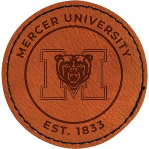 May include: A round, brown leather coaster with the Mercer University logo. The logo features a large letter "M" with a bear head in the center. The words "MERCER UNIVERSITY" and "EST. 1833" are also visible.