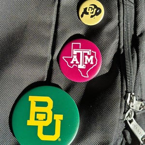 a close-up of a black bag with three colorful buttons attached to it.