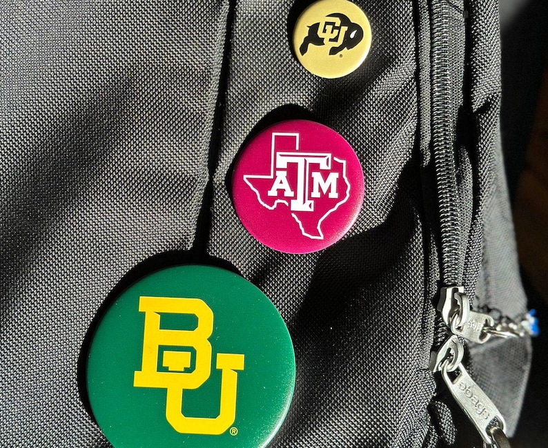 a close-up of a black bag with three colorful buttons attached to it.