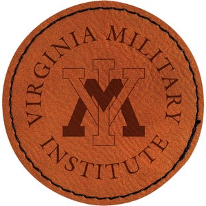 May include: A round, brown leather patch with the words "VIRGINIA MILITARY INSTITUTE" encircling a central emblem. The emblem features a stylized "V" and "M" intertwined. The patch has a black stitched border.