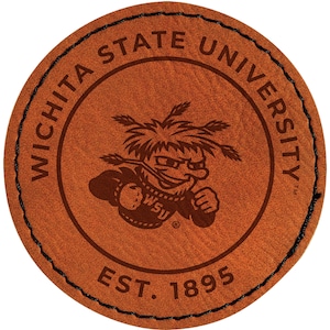 May include: A round, brown leather patch with the text "Wichita State University" encircling a cartoon mascot. The mascot is a stylized figure with a determined expression. The text "EST. 1895" is at the bottom, and the edge is stitched with black thread.