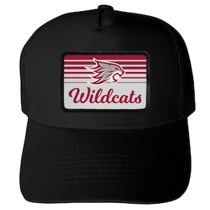 May include: A black trucker hat featuring a rectangular patch on the front. The patch displays a maroon and white striped background with a stylized grey and maroon wildcat head graphic above the maroon cursive text that reads Wildcats.