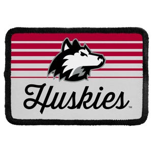 May include: A rectangular patch with a black stitched border featuring a graphic of a husky head in black, white, and gray. The background has horizontal red and white stripes above a white section with the word Huskies written in black script.