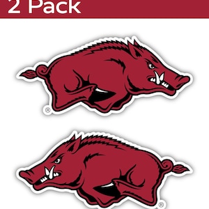 May include: Two red and black stickers featuring a Razorback mascot in a running pose. The stickers have a white border and are on a white background. The text "2 Pack" is in white on a red background.