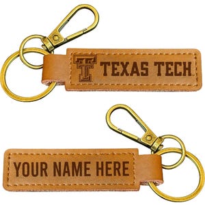 May include: Two brown leather keychains with gold-colored hardware. One keychain features the text "TEXAS TECH" and a logo. The other keychain has the text "YOUR NAME HERE".