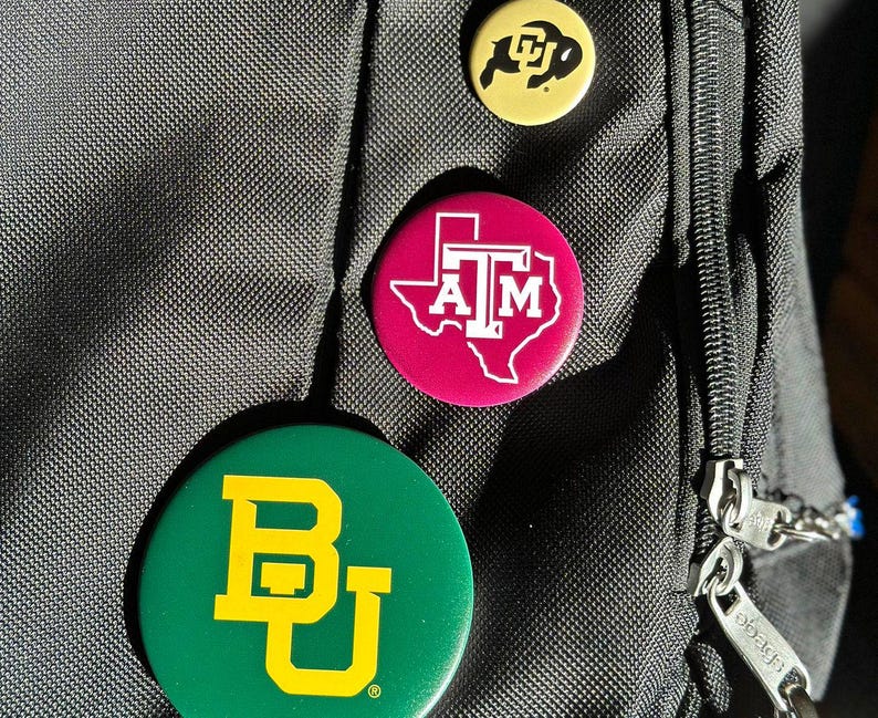 a close-up of a black bag with three colorful buttons attached to it.